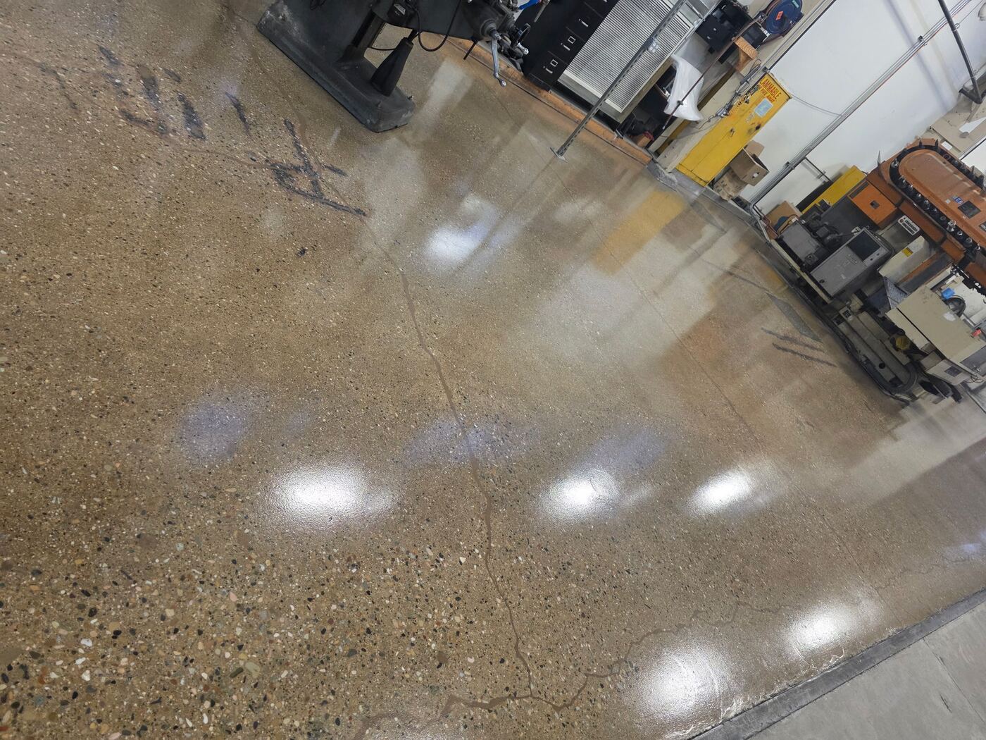 Glossy polished concrete floor reflecting overhead lights in a manufacturing facility